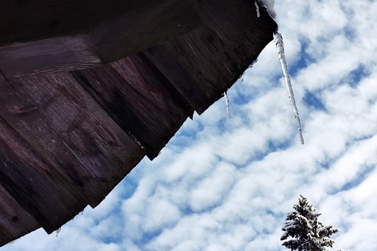 Blick in den Himmel mit Dach und herunterhängenden Eiszapfen