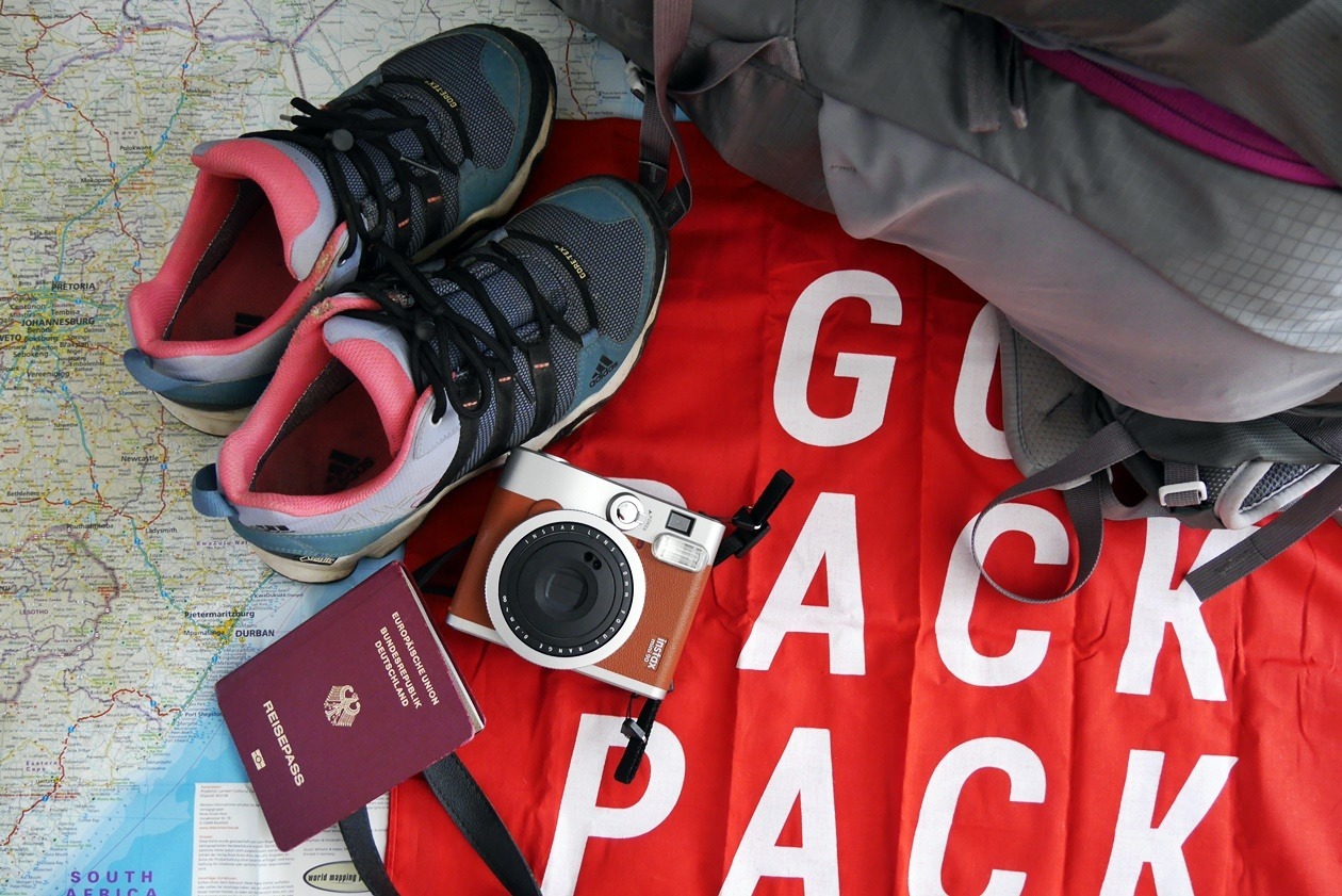 Schuhe, Rucksack und Reisepass, die zur Packliste Südafrika gehören