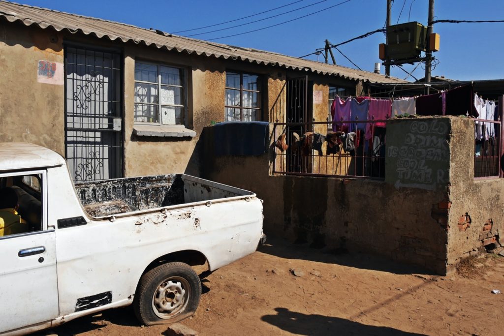 Auto mit kaputtem Reifen vor einem Wohnhaus in Soweto aufgenommen auf einer Fahrradtour durch Soweto mit Lebo´s Backpackers