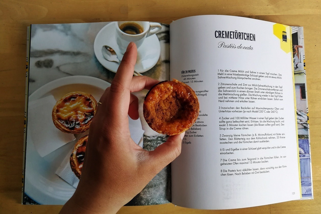 Hand mit Pastéis de Nata aus Lissabon - das Kochbuch
