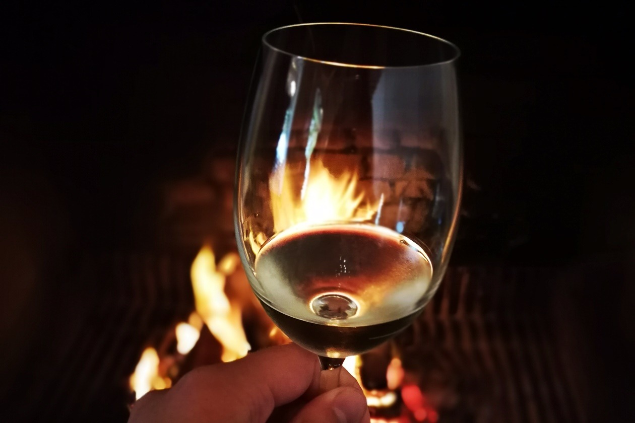 Glas Weißwein beim Winetasting vor einem Kaminfeuer in der Nähe von Kapstadt