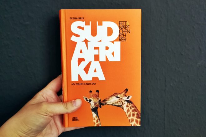 Hand mit dem Cover des Buches Fettnäpfchenführer Südafrika
