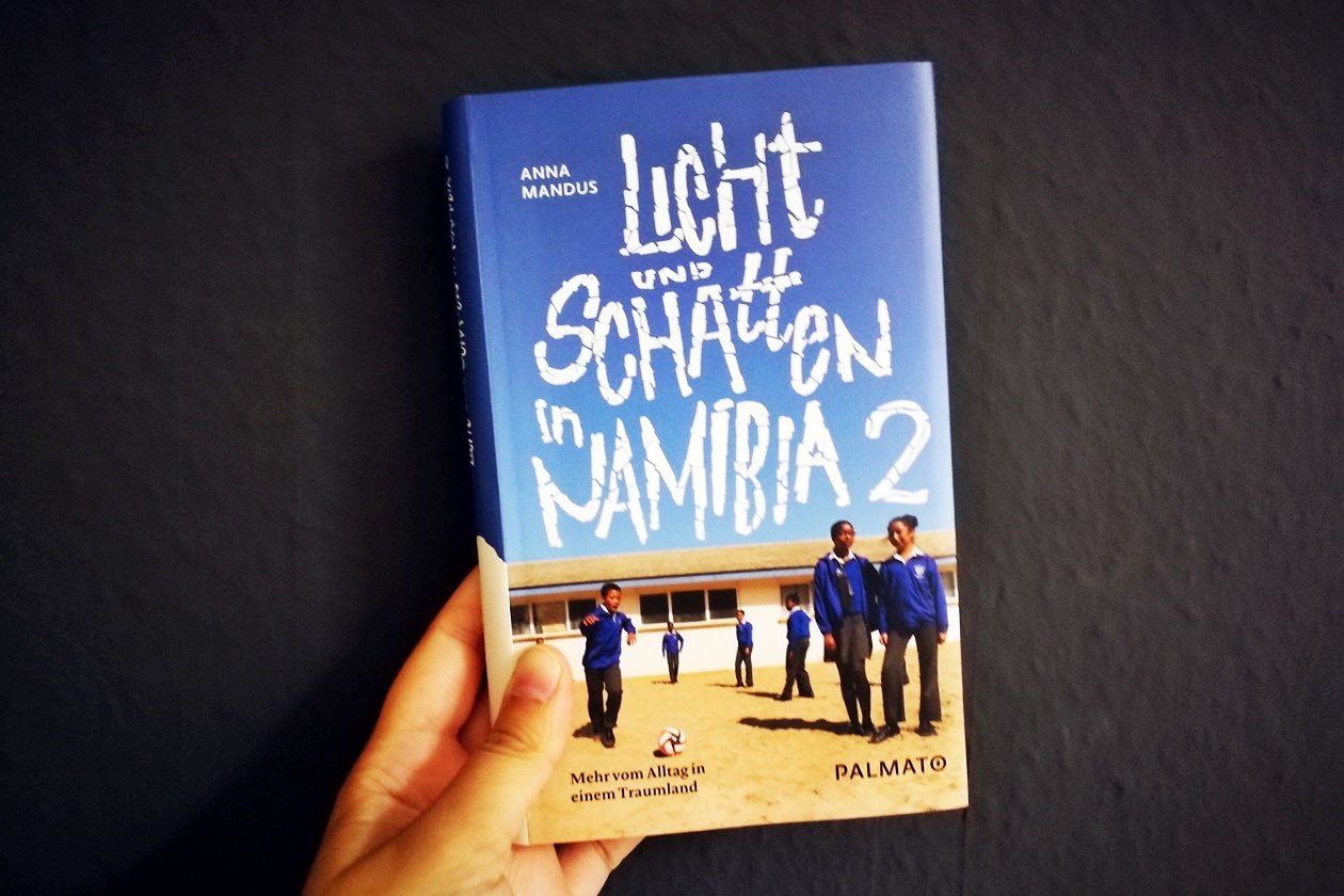 Hand die das Buch Licht und Schatten in Namibia 2 von Anna Mandus hält