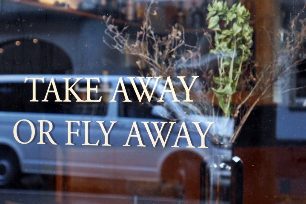 Schriftzug "Take Away or Fly Away" auf einem Schaufenster im Luzerner Bruchquartier