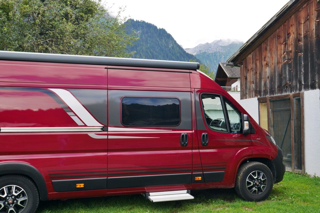 Camper Van, der auf einem Bergbauernhof in den österreichischen Alpen steht.