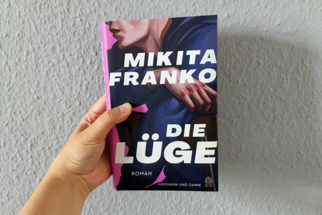 Hand die das Buch "Die Lüge" von Mikita Franko hochhält.