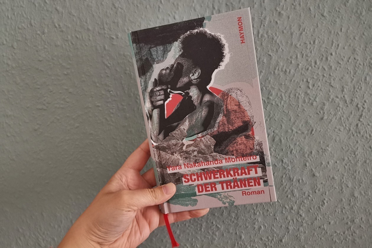 Hand die das Buch Schwerkraft der Tränen von Yara Nakahanda Monteiro hält