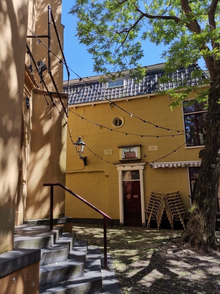 Gelbes Haus in den Straßen von Leeuwarden. Davor stehen Stühle gestapelt und hängen Lichterkette