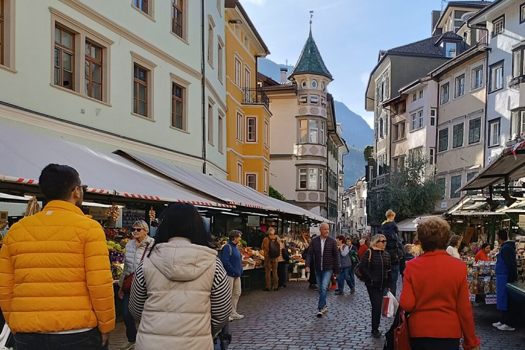 Altstadt von Bozen mit Marktständen und Besuchern, die durch die Gasse flanieren.