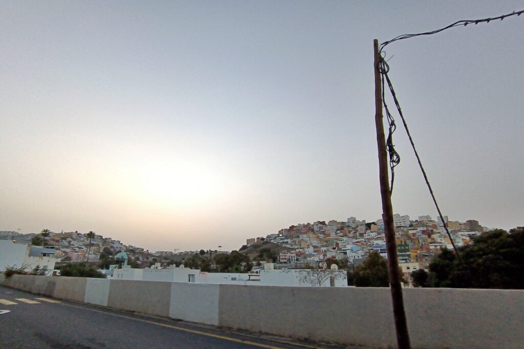 Blick bei Dämmerung auf einige Stadtviertel mit bunten Häusern von Las Palmas, die auf Hügeln liegen.