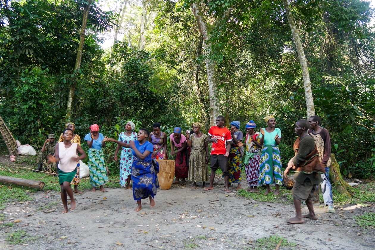 Batwa-Gruppe in traditioneller Kleidung tanzt und trommelt im Wald während der Buhoma Cultural Tour in Buhoma.