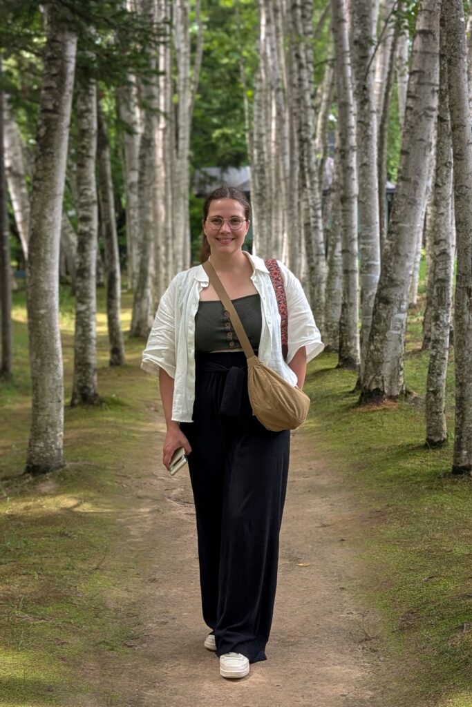 Frau spaziert durch einen Birkenwald in Hokkaido im Sommer, umgeben von hohen schlanken Bäumen.