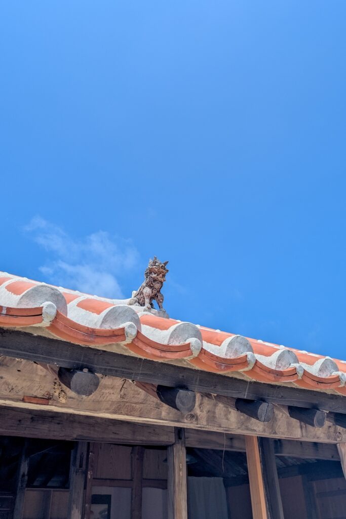 Shisa Figur mit offenem Mund auf einem roten Ziegeldach auf Taketomi.