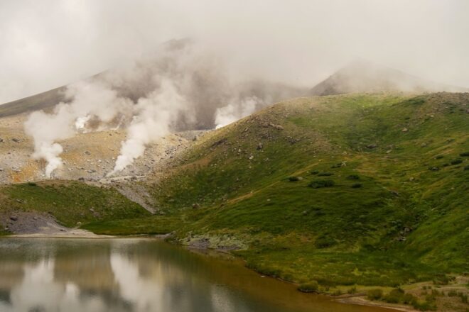 Blick auf die dampfenden Fumarole des Mt. Asahidake und dem davor liegenden Vulkansee.