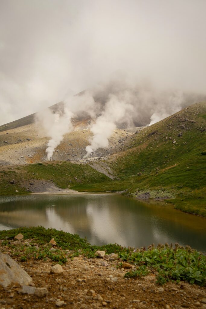 Blick auf die dampfenden Fumarole des Mt. Asahidake und dem davor liegenden Vulkansee.