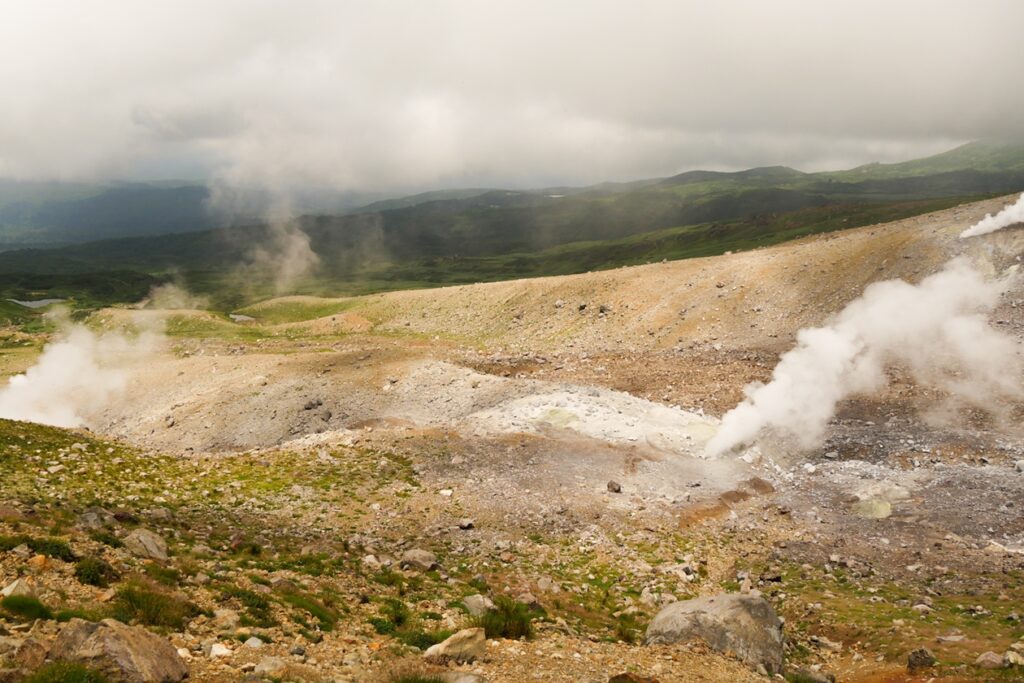 Blick vom Wanderweg zum Gipfel des Mt. Asahidake auf dampfende Fumarole. 