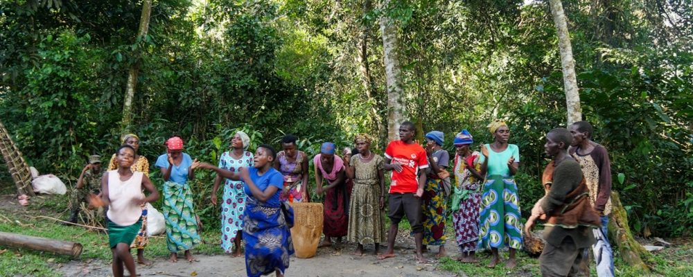 Batwa-Gruppe in traditioneller Kleidung tanzt und trommelt im Wald während der Buhoma Cultural Tour in Buhoma.