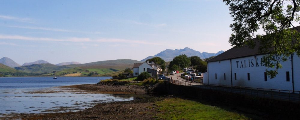 Bucht an der die Talisker Destillery liegt mit großen Bergen im Hintergrund auf der Isle of Skye